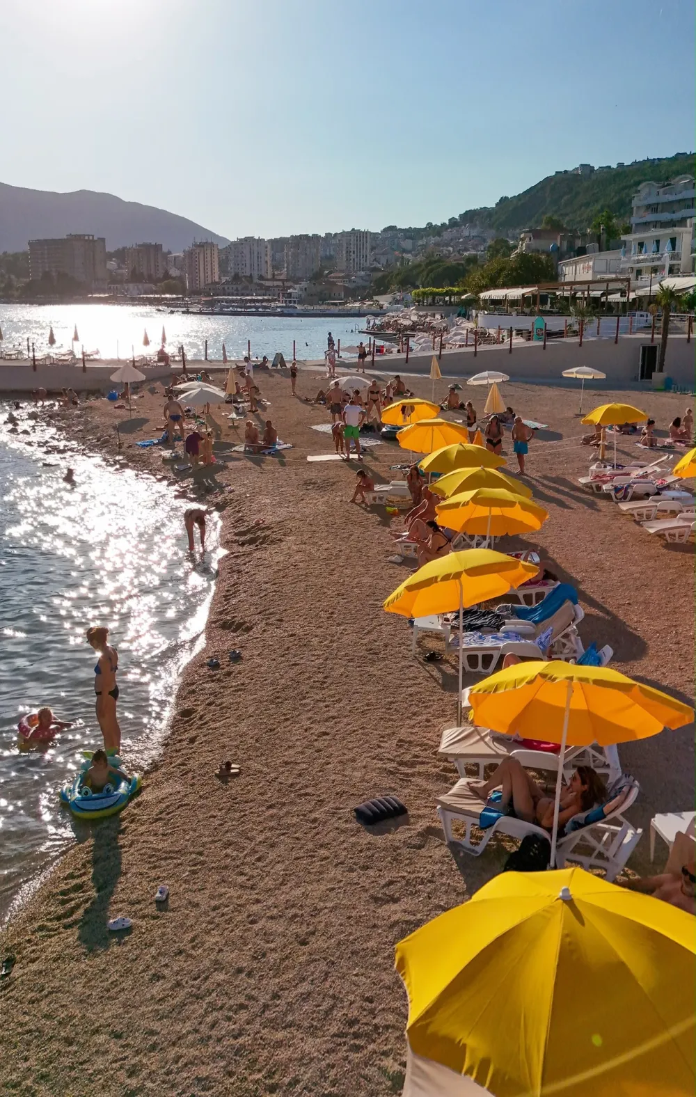 Plaža u kasnom popodnevnom svjetlu, žuti suncobrani uz obalu